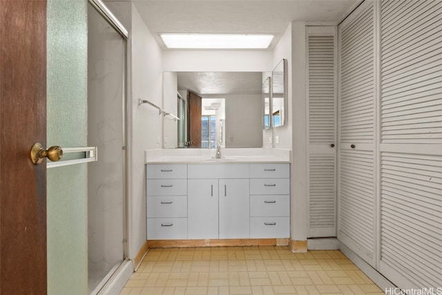 bathroom with a shower with door, vanity, and a skylight