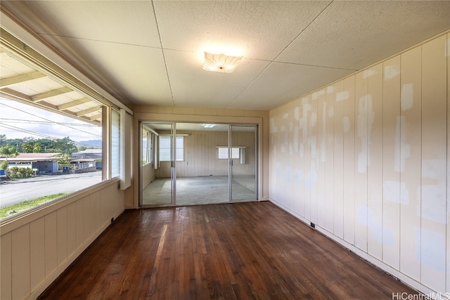 interior space with dark wood-type flooring, a healthy amount of sunlight, and wooden walls