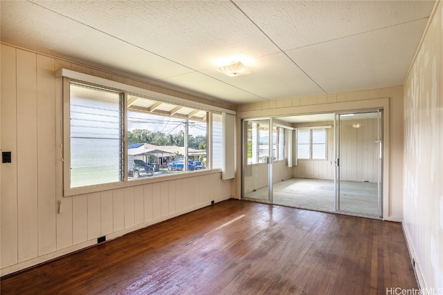 unfurnished bedroom featuring a closet, hardwood / wood-style floors, a textured ceiling, and wood walls