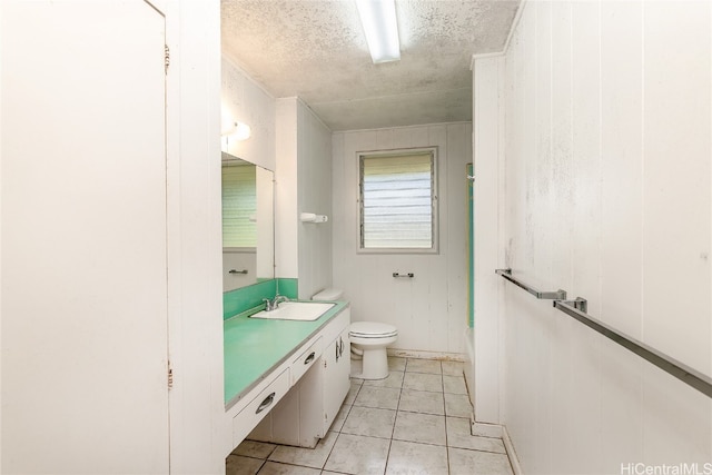 bathroom featuring a textured ceiling, toilet, wooden walls, vanity, and tile patterned flooring