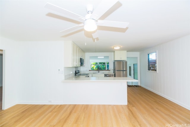 kitchen featuring light hardwood / wood-style flooring, white cabinets, stainless steel appliances, and kitchen peninsula