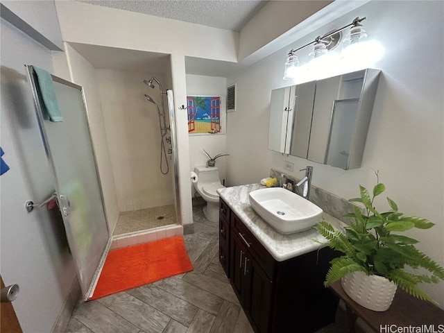 bathroom featuring vanity, tiled shower, a textured ceiling, and toilet