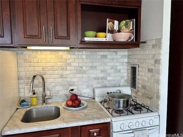 kitchen featuring sink, tasteful backsplash, and gas range gas stove