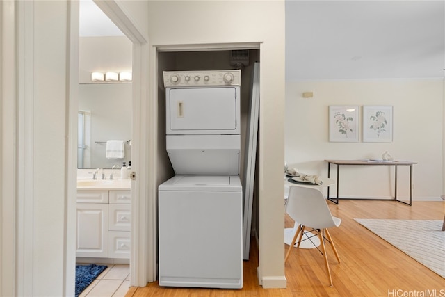 laundry area featuring light hardwood / wood-style floors, stacked washer and dryer, and sink