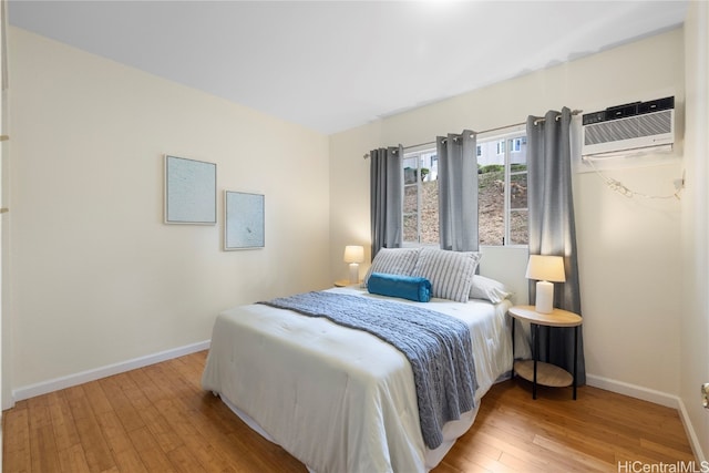 bedroom featuring light hardwood / wood-style floors and a wall unit AC