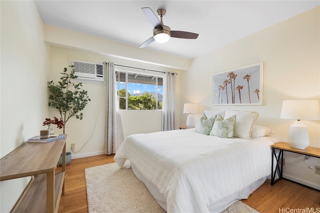 bedroom with light hardwood / wood-style floors, a wall unit AC, and ceiling fan