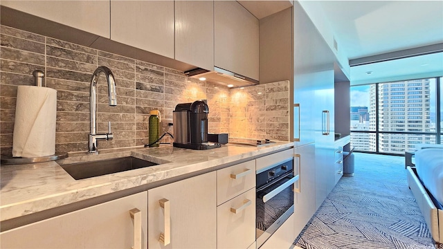 383 Kalaimoku St Unit E2001, Honolulu, HI 96815 - kitchen with a sink, light stone countertops, wall oven, under cabinet range hood, and tasteful backsplash