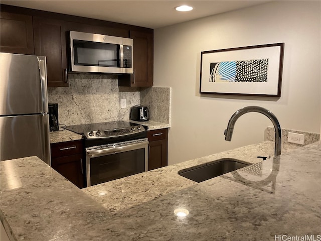 kitchen with light stone counters, appliances with stainless steel finishes, sink, and decorative backsplash