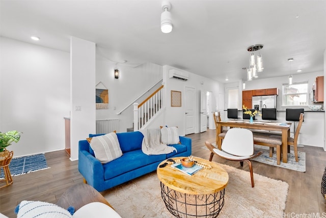 living room with light hardwood / wood-style floors and an AC wall unit