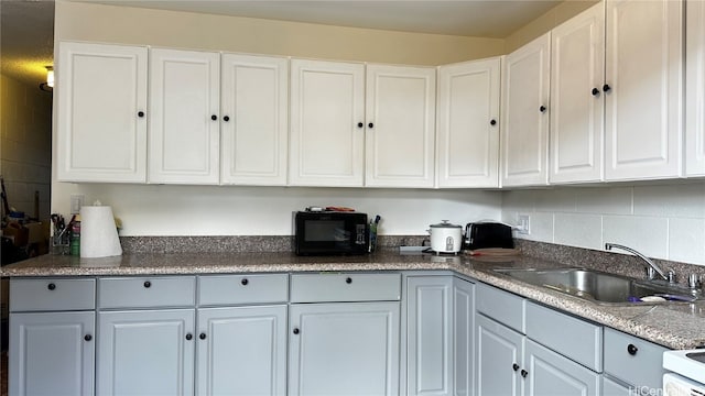 kitchen featuring white cabinets, white range, backsplash, and sink