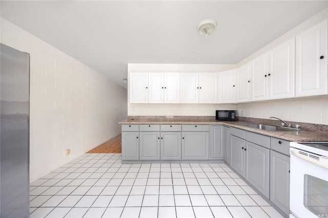 4280 Salt Lake Blvd Unit H11, Honolulu, HI 96818 - kitchen with white electric range, white cabinetry, black microwave, freestanding refrigerator, and light tile patterned floors