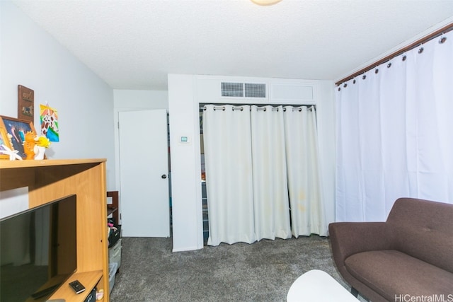 living area featuring a textured ceiling and dark carpet