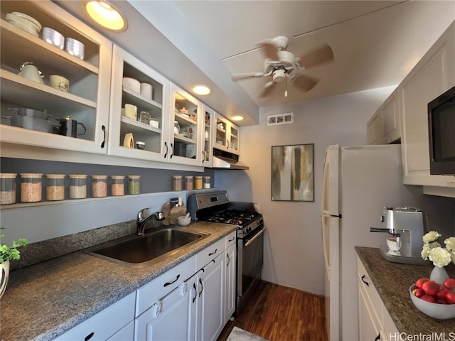 kitchen featuring dark hardwood / wood-style floors, stainless steel gas range, sink, white cabinetry, and white fridge