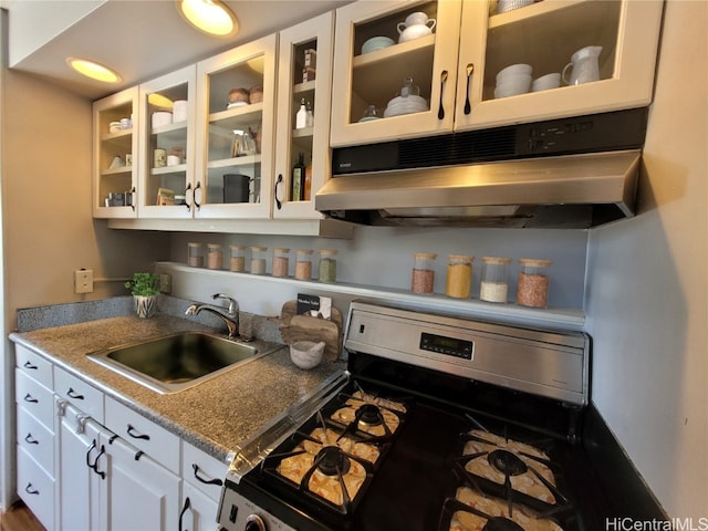 kitchen featuring white cabinetry, stainless steel stove, sink, and light stone counters