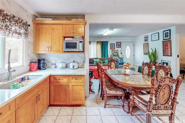 kitchen featuring sink, light tile patterned flooring, a textured ceiling, and tasteful backsplash