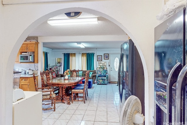 dining space featuring a textured ceiling and light tile patterned flooring