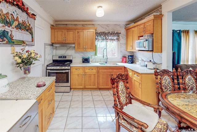 kitchen featuring decorative backsplash, a textured ceiling, ornamental molding, sink, and stainless steel appliances