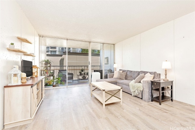 living room featuring a wall of windows, a textured ceiling, and light wood-type flooring