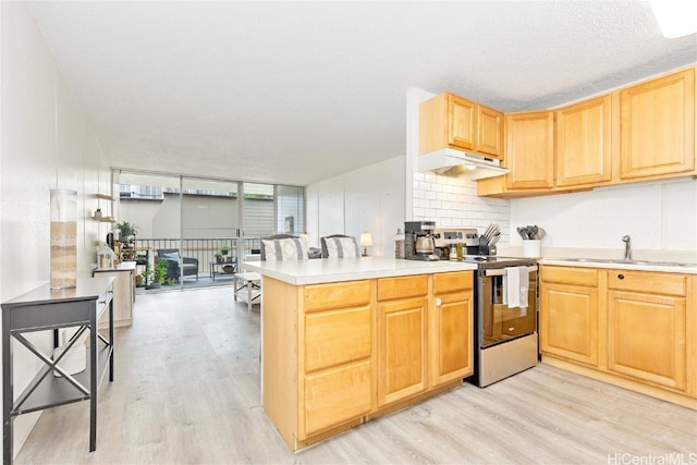 kitchen with kitchen peninsula, sink, stainless steel electric range, light wood-type flooring, and a textured ceiling