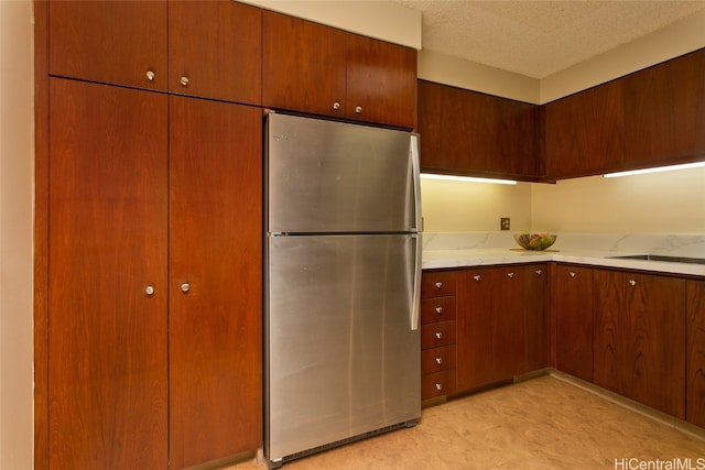 kitchen featuring a textured ceiling and stainless steel fridge