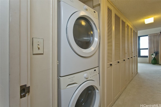 laundry area featuring stacked washer and dryer, light carpet, and a textured ceiling