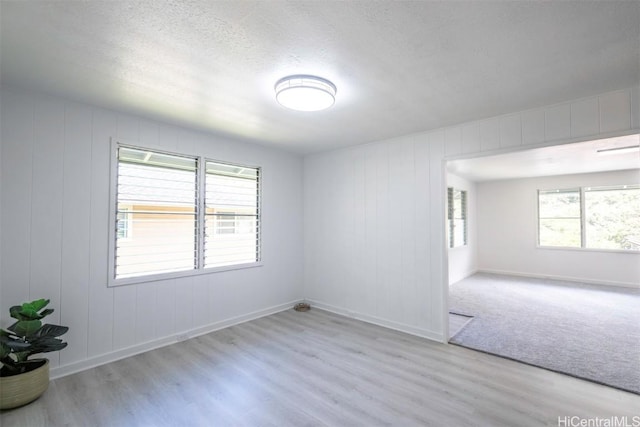 empty room featuring a textured ceiling and light hardwood / wood-style floors