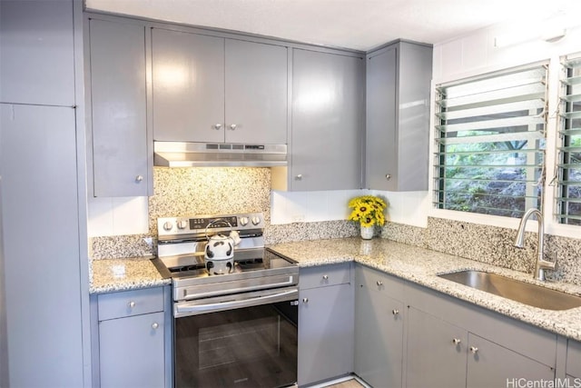 kitchen with sink, gray cabinets, backsplash, light stone countertops, and stainless steel electric stove