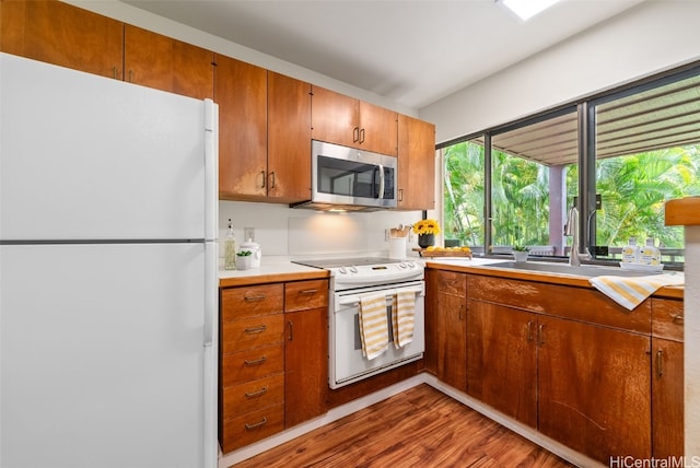 kitchen featuring white appliances, wood-type flooring, and sink