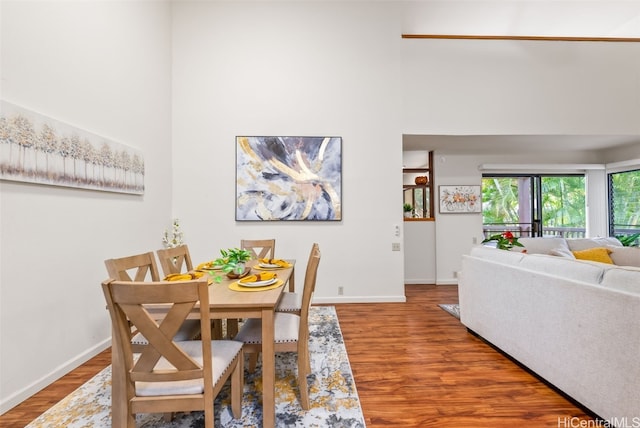 dining area with a towering ceiling and hardwood / wood-style floors