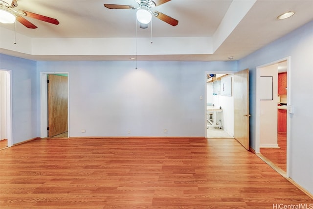 unfurnished room with a tray ceiling, light hardwood / wood-style flooring, and ceiling fan