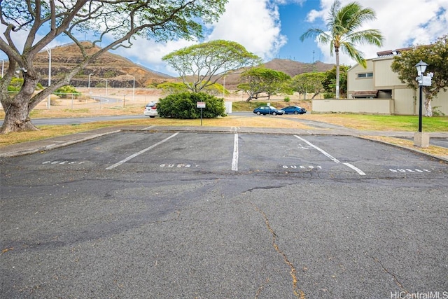 uncovered parking lot featuring fence and a mountain view