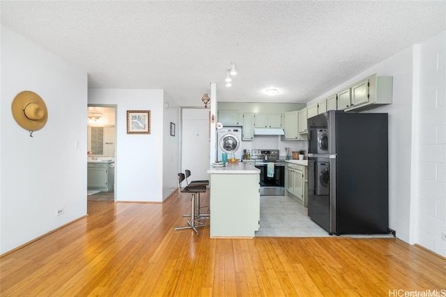 kitchen with a kitchen island, appliances with stainless steel finishes, a breakfast bar, a textured ceiling, and light wood-type flooring