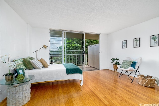 bedroom featuring a textured ceiling, hardwood / wood-style flooring, and access to exterior