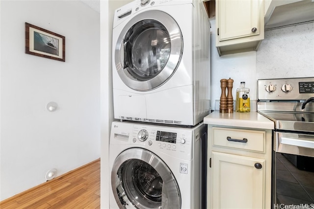 laundry area featuring stacked washer and clothes dryer and light wood-type flooring