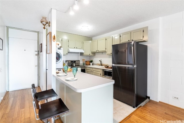 kitchen with light hardwood / wood-style floors, stainless steel appliances, a textured ceiling, and kitchen peninsula