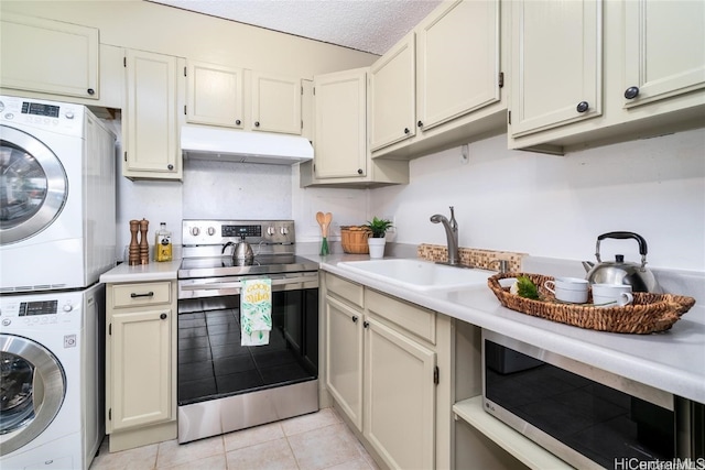 kitchen with a textured ceiling, stacked washer / drying machine, light tile patterned flooring, sink, and stainless steel appliances