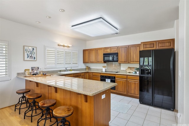 2897 Kalawao St Unit 61, Honolulu, HI 96822 - kitchen featuring black appliances, a peninsula, brown cabinets, and a breakfast bar area