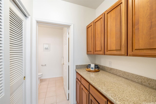 2897 Kalawao St Unit 61, Honolulu, HI 96822 - kitchen with brown cabinets, light tile patterned floors, and light stone counters