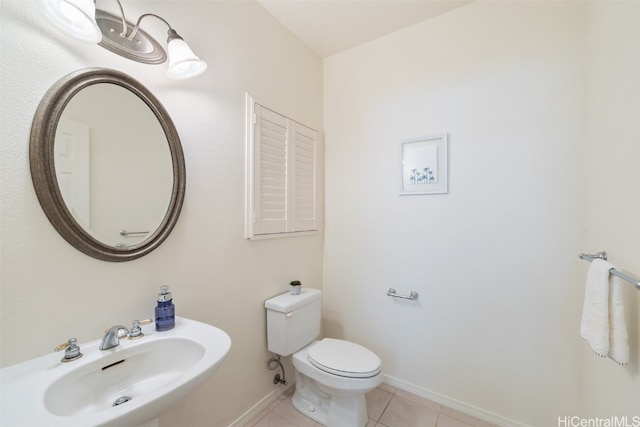 bathroom with toilet, sink, and tile patterned floors