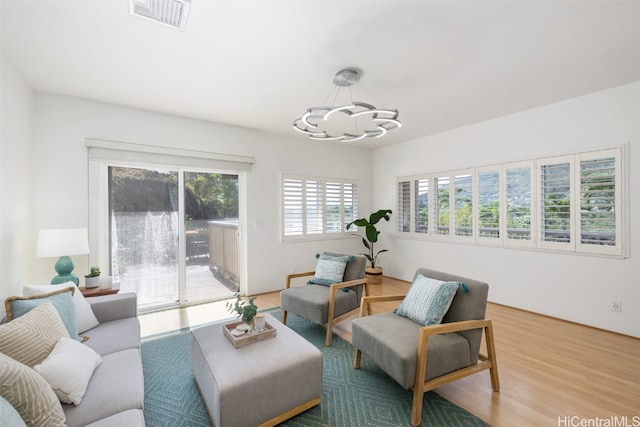 living area with a notable chandelier, wood finished floors, and visible vents