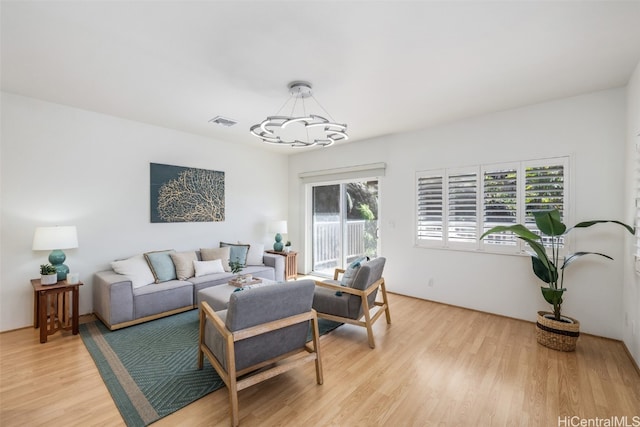 living room with light hardwood / wood-style flooring, a chandelier, and a wealth of natural light