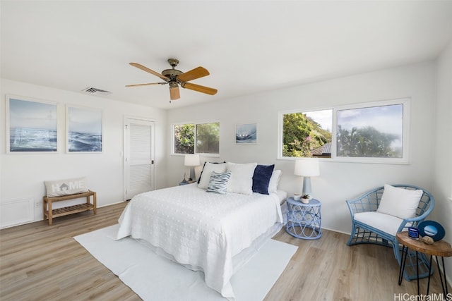 bedroom featuring light hardwood / wood-style flooring, multiple windows, a closet, and ceiling fan