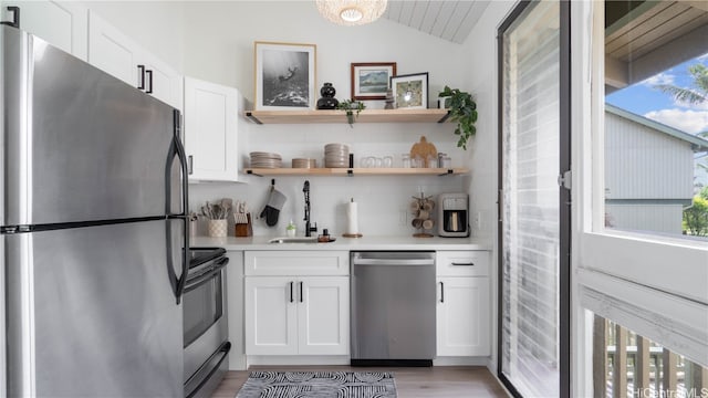 kitchen featuring appliances with stainless steel finishes, lofted ceiling, white cabinetry, and sink