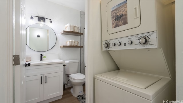 bathroom with toilet, stacked washer / drying machine, hardwood / wood-style flooring, and vanity