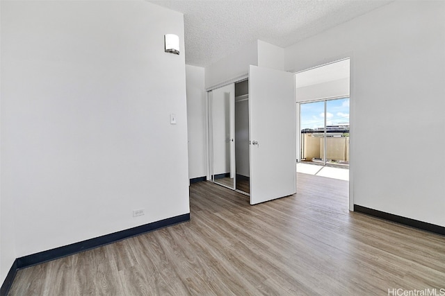 unfurnished bedroom with a closet, light hardwood / wood-style floors, and a textured ceiling