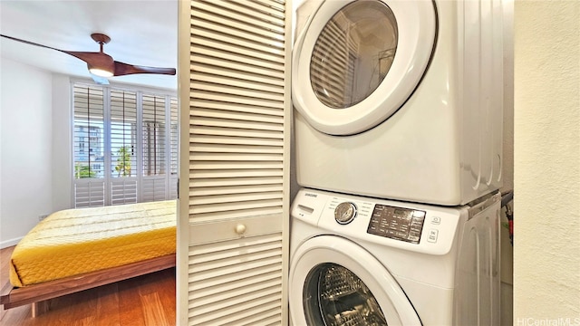 washroom with hardwood / wood-style floors and stacked washer / dryer