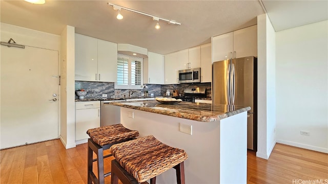 kitchen featuring light hardwood / wood-style floors, white cabinets, stainless steel appliances, and a kitchen island