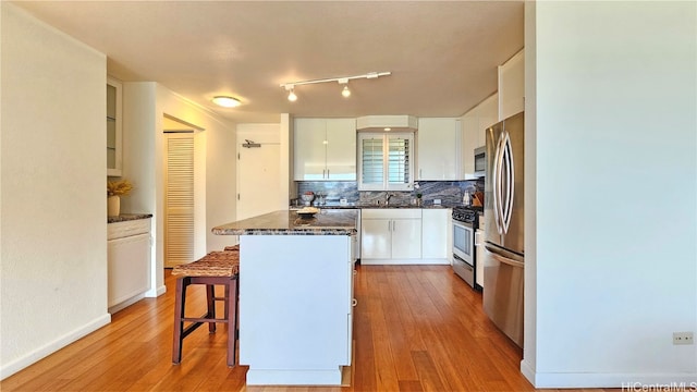 kitchen featuring stainless steel appliances, light wood-type flooring, a kitchen breakfast bar, and white cabinets