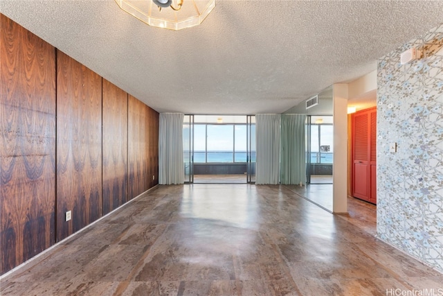 empty room featuring wood walls, a textured ceiling, and concrete flooring