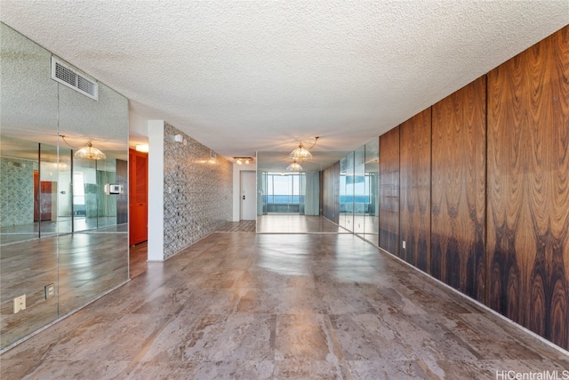 empty room featuring wood walls and a textured ceiling